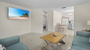 Una sala de estar moderna con una mesa de centro de madera, sofás color turquesa y un cuadro grande con temática de playa en la pared.