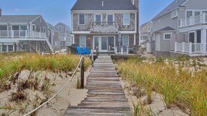 A beachfront property with a wooden boardwalk leading to a house with a balcony. - Waterfront cottage with private beach in Sandwich! 179B North Shore Blvd (Sandwich)