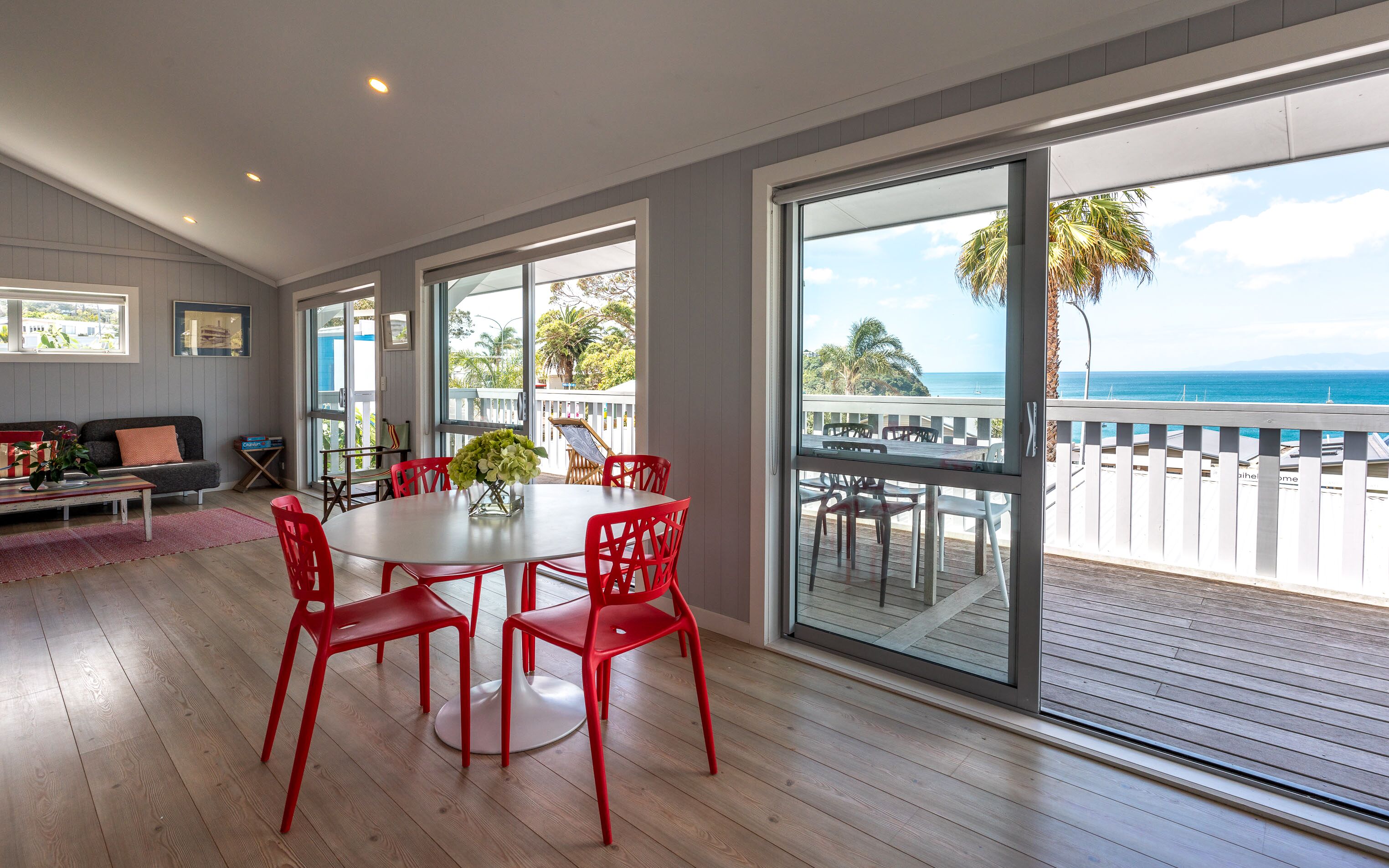 Quarto amplo com uma grande janela com vista para um deck e para o oceano.