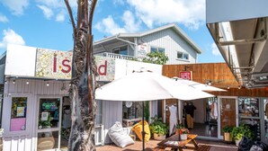 A beachfront property with a sign reading "Island," a wooden fence, and a beach umbrella. - THE WAIHEKE PAD | Be My Guest (Oneroa)