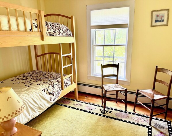 Una habitación con literas, una silla, un ventanal y una alfombra.