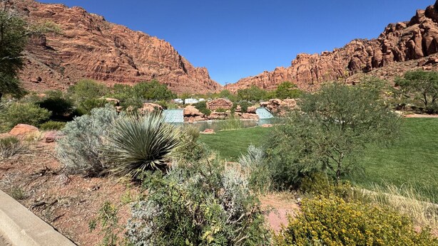 A desert landscape with red rock formations, green vegetation, and a clear blue sky. - Peaceful Sports Village Retreat | Beautiful Mountain Views, Pools & Patio (St George)