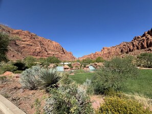 A desert landscape with red rock formations, green vegetation, and a clear blue sky. - Peaceful Sports Village Retreat | Beautiful Mountain Views, Pools & Patio (St George)