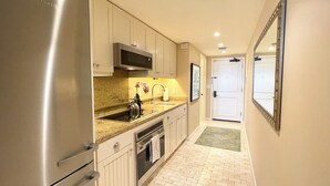 Una cocina moderna con electrodomésticos de acero inoxidable, encimera de granito y salpicadero azulejado.