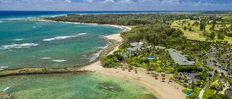 A coastal resort with a beach, clear waters, and lush greenery.