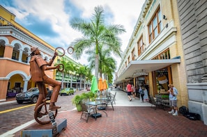 A street scene with a statue of a horse, palm trees, and a building with a sign that reads "Scoops on First." - Summerlin Woods - Second floor condo (Fort Myers)