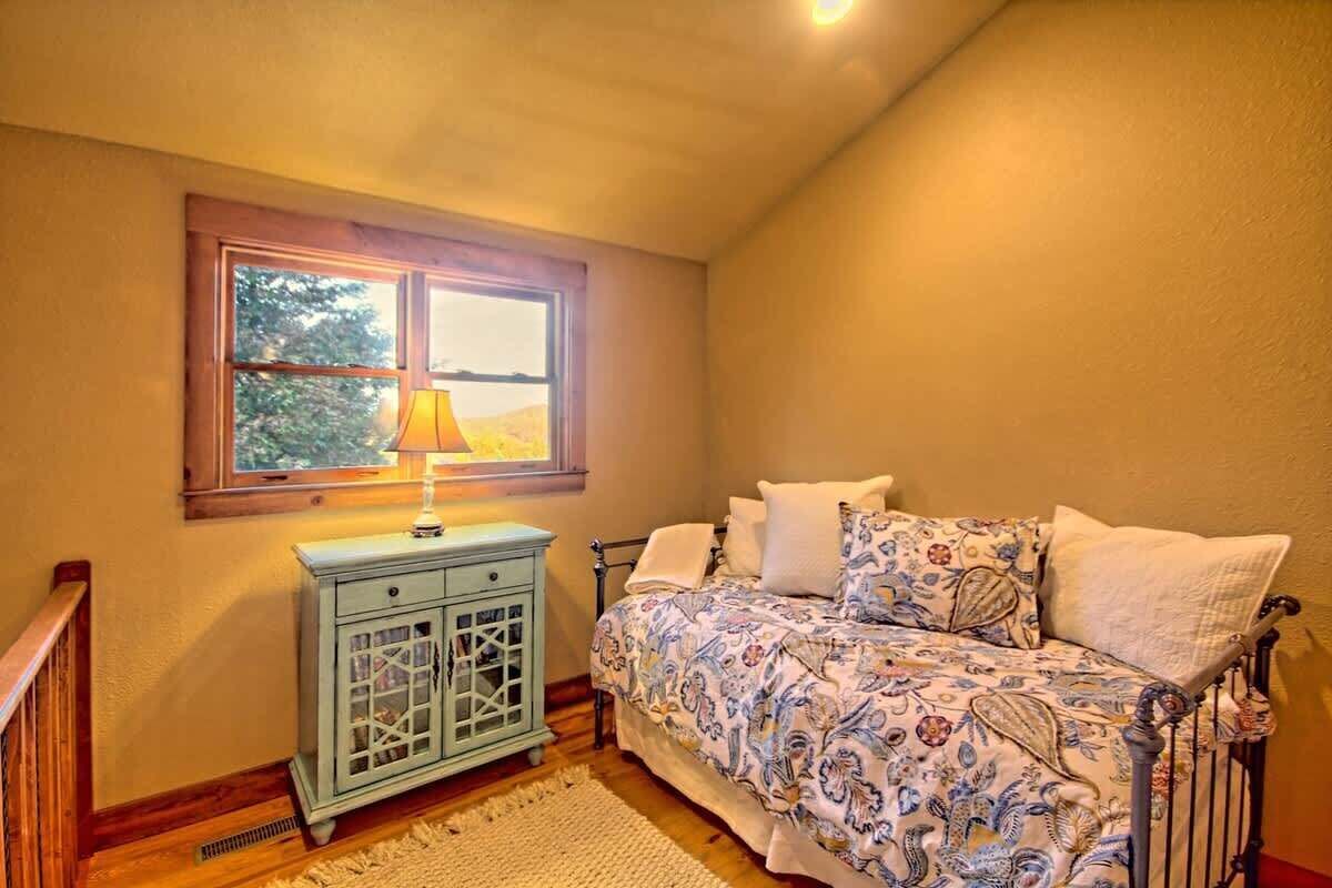 A bedroom with a bed, a nightstand, a window, and a lamp.