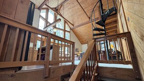 A wooden interior with a spiral staircase and large windows. - Ski-in Ski-out Killington Chalet on Great Eastern Trail, Huge Loft + 4 Bedrooms (Killington)