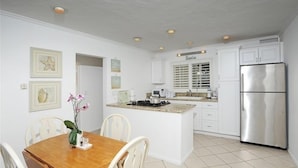 A modern kitchen with white cabinetry, a stainless steel refrigerator, and a central island with a gas stove. - Oceanfront Retreat on Sandy Carbon Beach - Dolphin (Malibu)