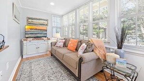 A living room with a beige sofa, a patterned rug, a television, and artwork on the wall.