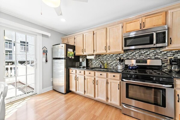 A modern kitchen with wooden cabinets, stainless steel appliances, and a black countertop. - **3rdtoBeach*BIG DISCOUNTS SUMMER WEEKS*Heart of BEACH HAVEN*Across Veterans PRK (Beach Haven)