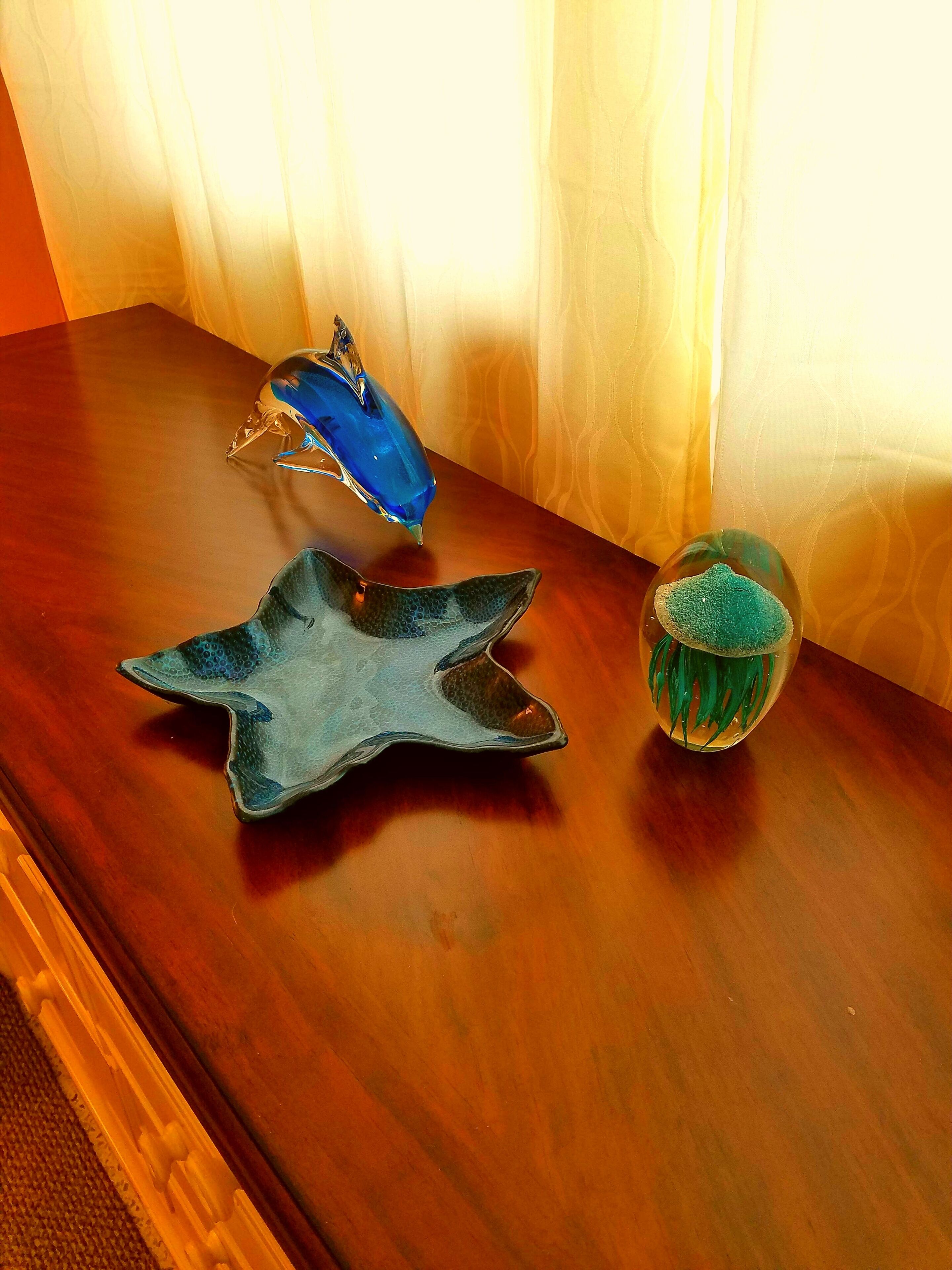 Three glass art pieces on a wooden table.