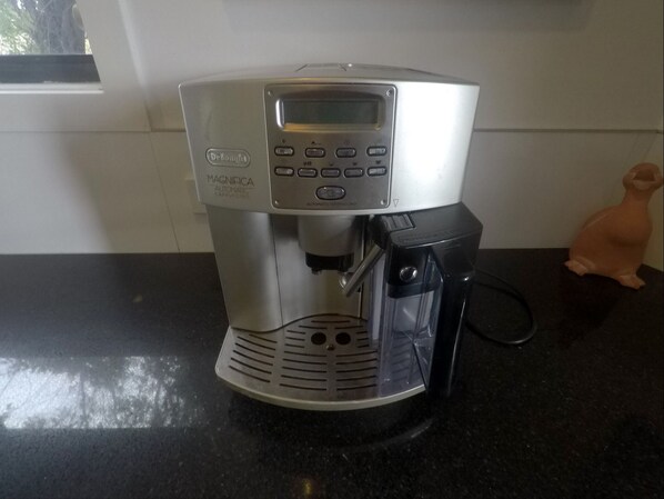 Une machine à café automatique De'Longhi Magnifica posée sur un plan de travail de cuisine.