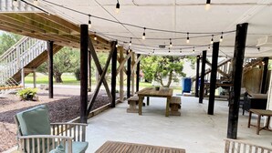 An outdoor patio area with wooden furniture, string lights, and a covered seating area. - Prior Engagement: Pet Friendly Beach Cottage at Emerald Isle on The Point (Emerald Isle)