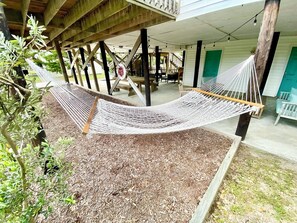 A hammock under a wooden structure with a view of a building and outdoor furniture. - Prior Engagement: Pet Friendly Beach Cottage at Emerald Isle on The Point (Emerald Isle)