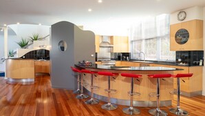 Een moderne keuken met een centraal eiland, barkrukken en een groot raam.