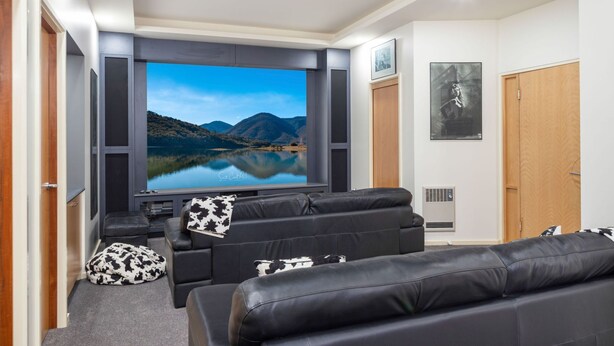 Een moderne woonkamer met een grote flatscreen-televisie, leren banken en een gezellige sfeer.