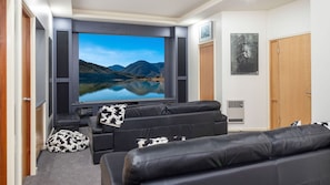 A modern living room with a large flat-screen TV, leather sofas, and a cozy ambiance. - Seacrest at the Bay (CATALINA)