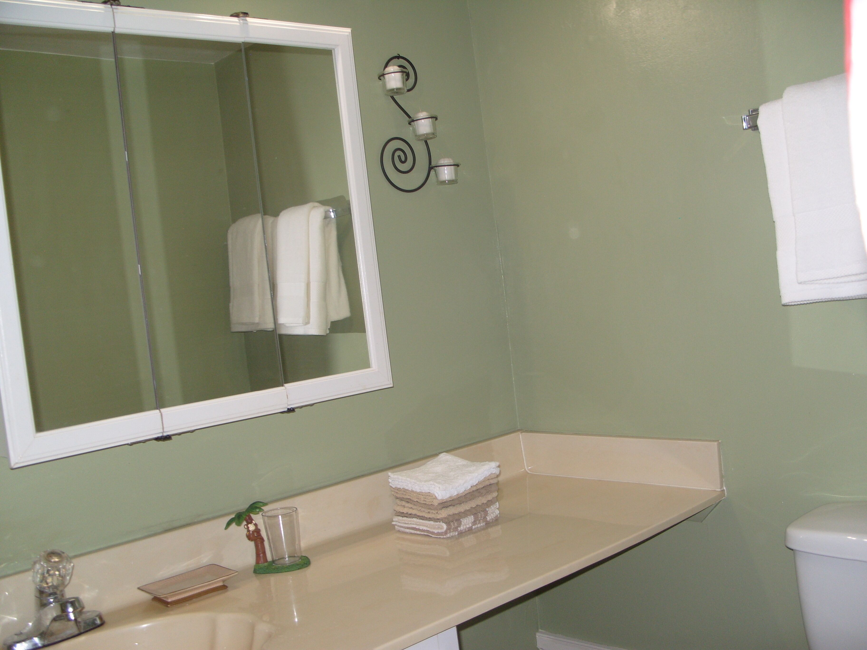 A bathroom with a mirror, sink, and toilet.