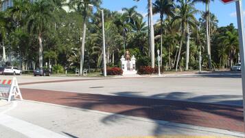 Una intersección de calles con palmeras, una señal de alto y una estatua en el centro.