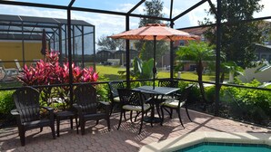 Un espacio al aire libre techado con piscina, mobiliario de patio y vistas del paisaje circundante.
