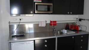 Una cocina equipada con microondas, hervidor y cafetera.