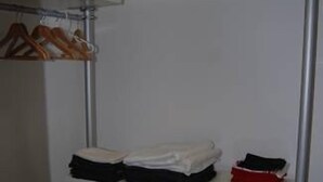 Un armario con estantes y cajones, que contiene ropa doblada y perchas.