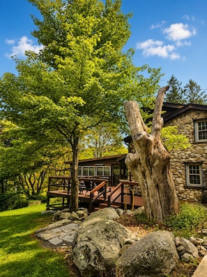 A stone building with a wooden deck and a large tree in front. - Brech Mountain House-Hudson Valley (Pine Bush)