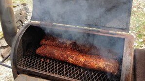 Een barbecue met een groot stuk vlees dat er bovenop wordt gebakken.