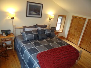A bedroom with a bed, bedside tables, a nightstand, a window, and a door.