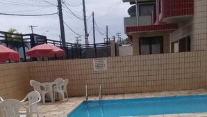 A swimming pool with tiled flooring and a small set of plastic chairs. - Apartment with ocean view. 2 bedrooms. BORACEIA BEACH (boraceia)