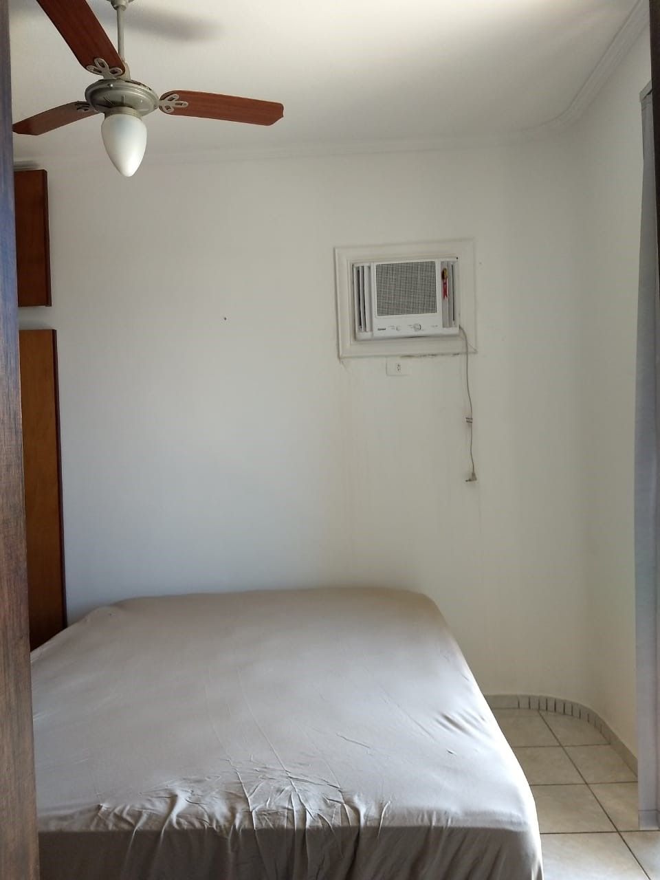 Une chambre avec un lit simple, un ventilateur de plafond et un appareil de climatisation.