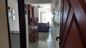 A hallway leading to a dining area with a table and chairs, a sofa, and a ceiling fan. - Apartment with ocean view. 2 bedrooms. BORACEIA BEACH (boraceia)