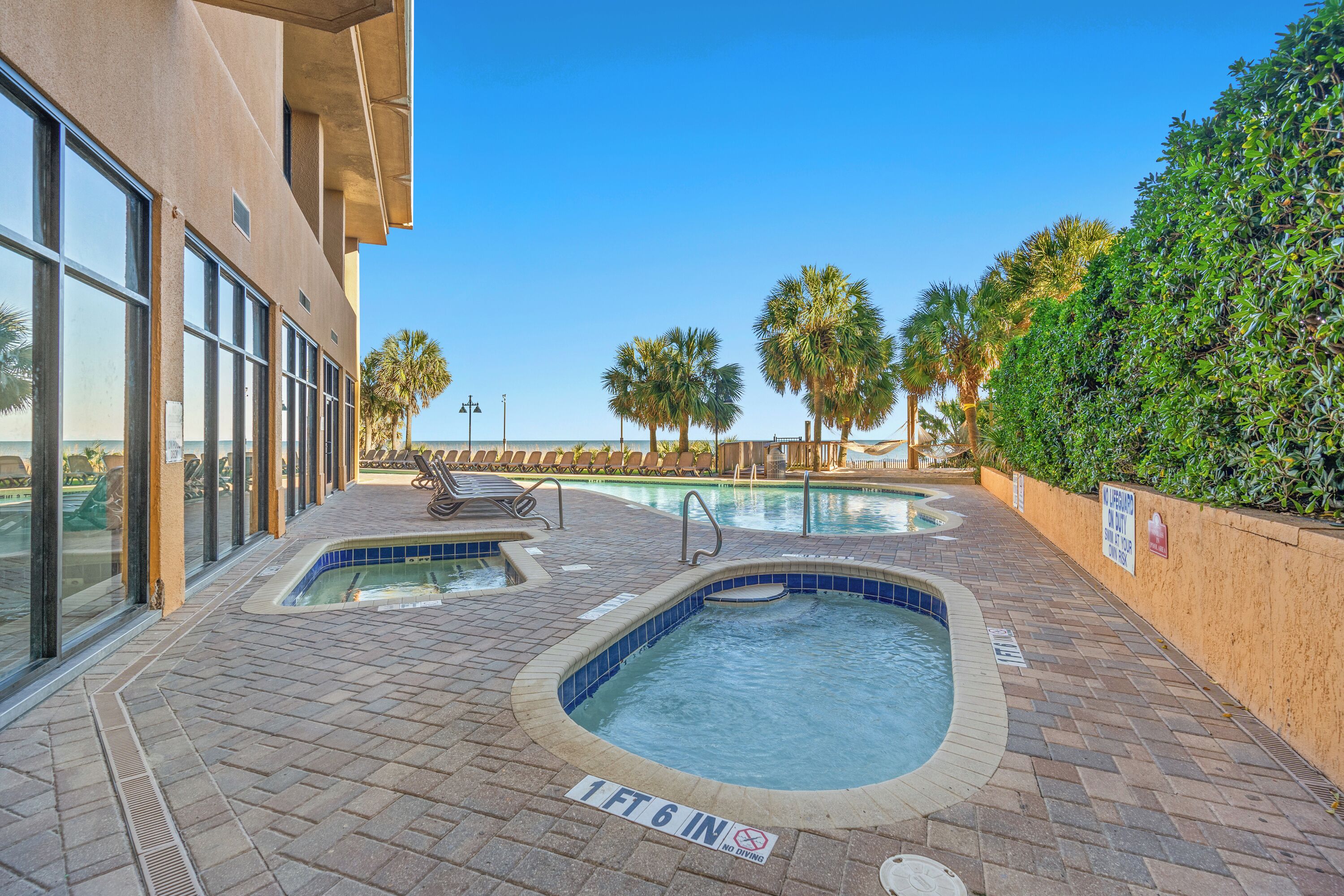 An outdoor swimming pool area with lounge chairs and a sign indicating a depth of 1 ft 6 in.