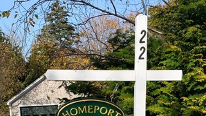 A house number sign for Homeport 22, with a garage in the background. - Oceanfront Cape with dock on Bass Harbor (Bernard)