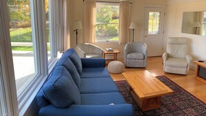 A modern living room with a blue sofa, patterned armchairs, a wooden coffee table, and a patterned rug. - Oceanfront Cape with dock on Bass Harbor (Bernard)