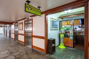 A hallway with elevators, a coffee shop entrance, and a vending machine.