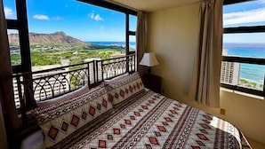 Une chambre avec un grand lit, un balcon offrant une vue sur un paysage montagneux et une fenêtre avec des rideaux.