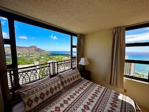 Ein Schlafzimmer mit einem großen Bett, einem Balkon mit Blick auf eine Berglandschaft und einem Fenster mit Vorhängen.