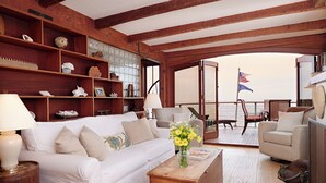 En hyggelig stue med en hvid sofa, træhylder og udsigt til terrassen med et amerikansk flag.
