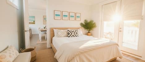 A bedroom with a bed, a ceiling fan, a potted plant, and a view of the outdoors.