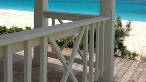A wooden deck with a white railing overlooking a beach with clear turquoise water. - Aqua Dreams, Htd Priv Salt Pool, At Beach, Guest hse, 4 Kng BRs for 12, Lg Spa!! (Georgetown)