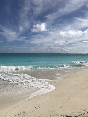 Ein Strand mit blauem Himmel und ruhiger Wellenbewegung.