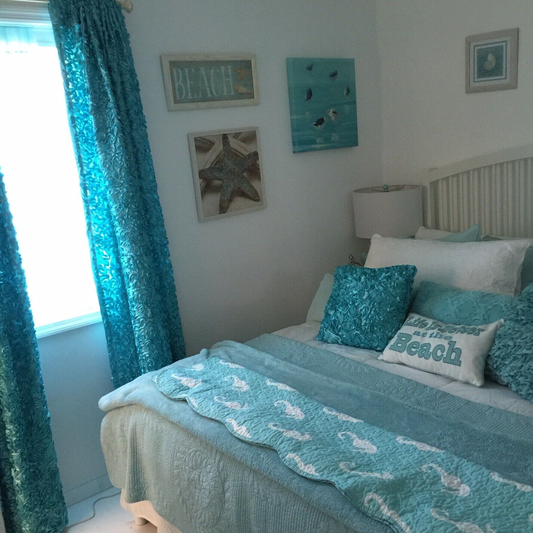 A bedroom with a bed, pillows, and wall art.