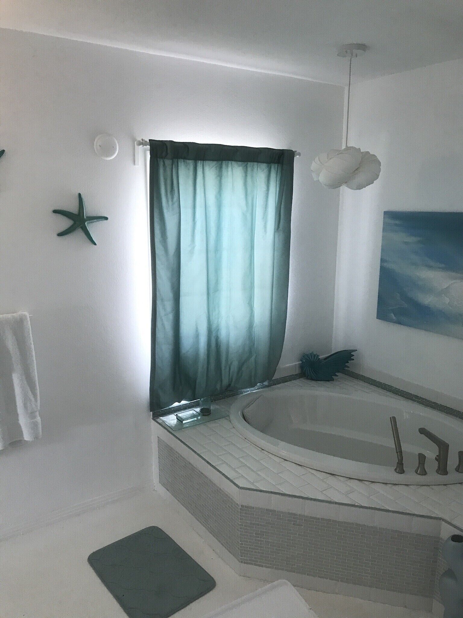 Ein Badezimmer mit einer Badewanne, einer Meerstern-Dekoration, einem Handtuchhalter und einem Bild an der Wand.