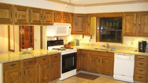 A kitchen with wooden cabinets, a stove, microwave, sink, and dishwasher. - Island Lake Redwood Cottage With Canoe and Grill:  Relax, Swim, Fish, Ski, Enjoy (Fort McCoy)