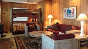 A cozy room with a bunk bed, a sofa, a coffee table, and two lamps. - Island Lake Redwood Cottage With Canoe and Grill:  Relax, Swim, Fish, Ski, Enjoy (Fort McCoy)