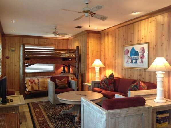 A cozy room with a bunk bed, a sofa, a coffee table, and two lamps.