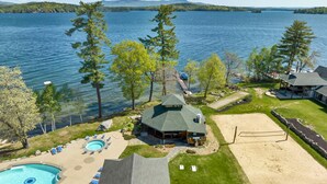 A lakeside property with a swimming pool, a tennis court, and a cabin-style building. - 🏖 Lake Winnipesaukee Vacation at Akwa Marina 🏖 Beach, Pool, Hot Tub, Beach Bar (Laconia)