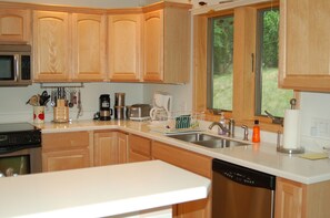 Una cocina con armarios de madera, microondas, cafetera y lavavajillas.